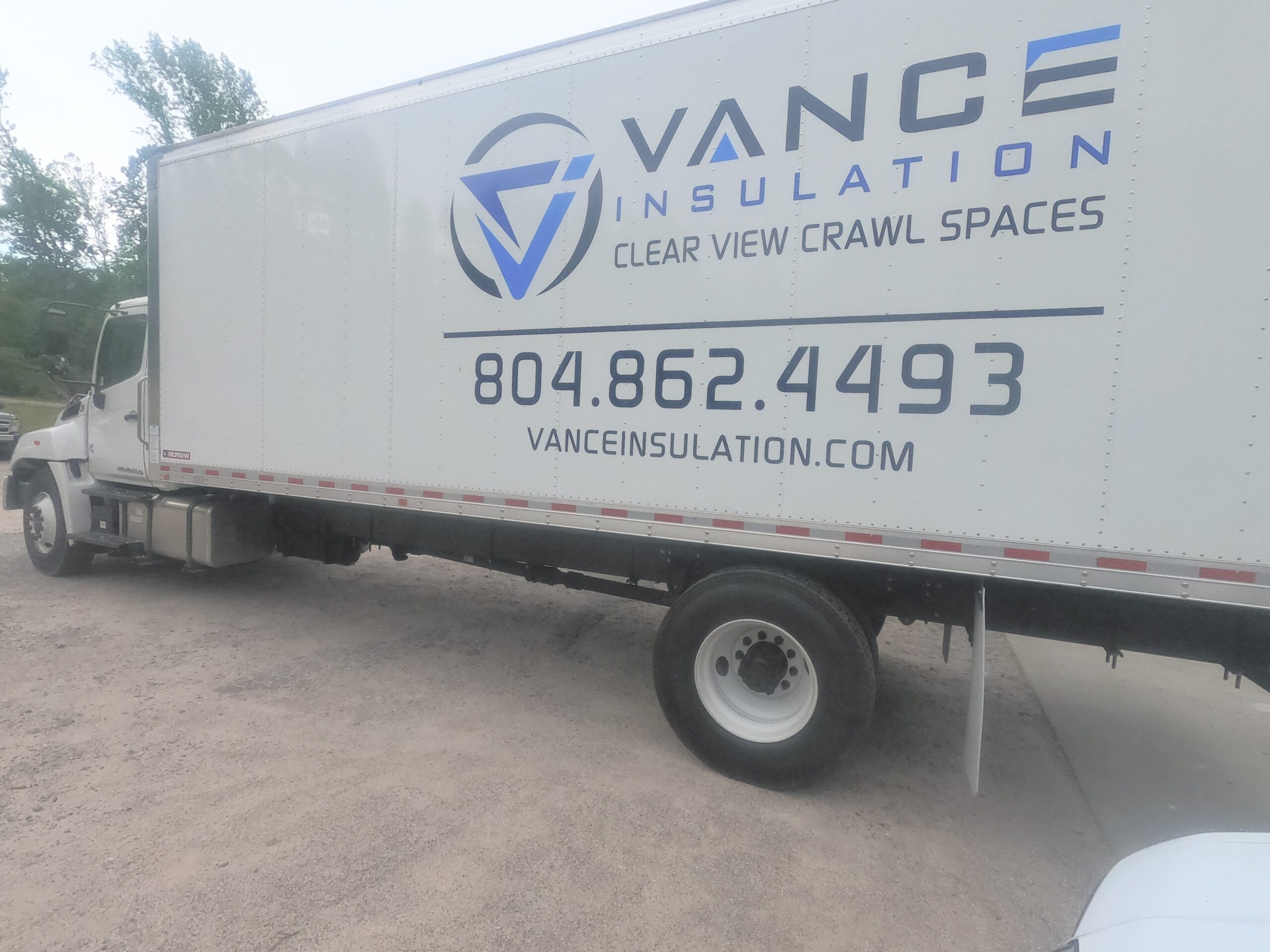 A Vance Insulation box truck parked on gravel, displaying the company logo, contact phone number, and website on the side.